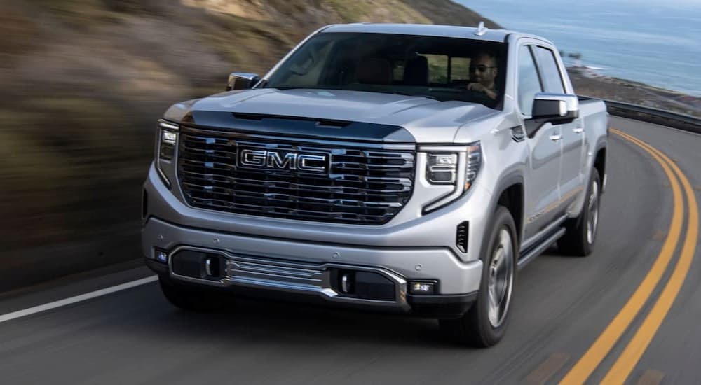A silver 2024 GMC Sierra 1500 is shown driving on a highway.