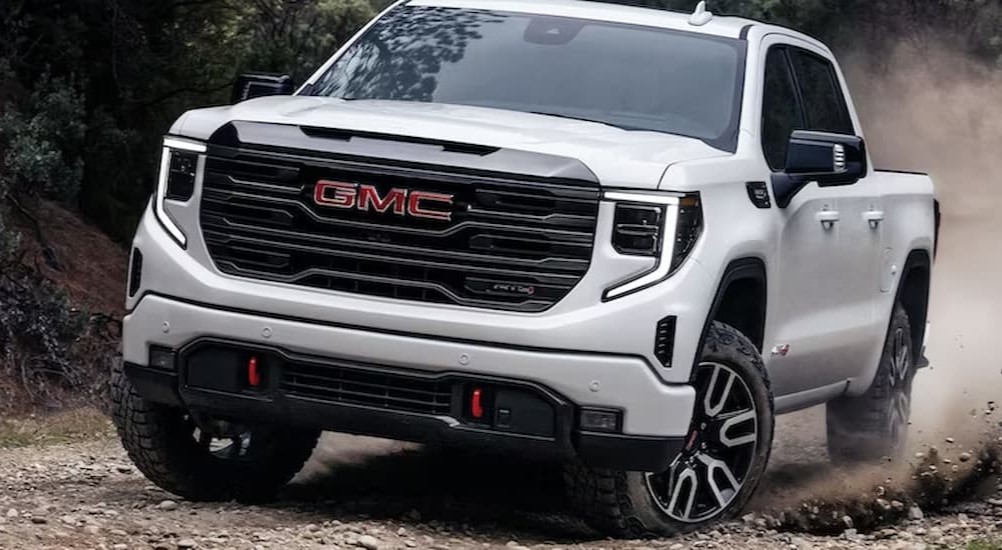 A white 2024 GMC Sierra 1500 AT4X is shown driving off-road.