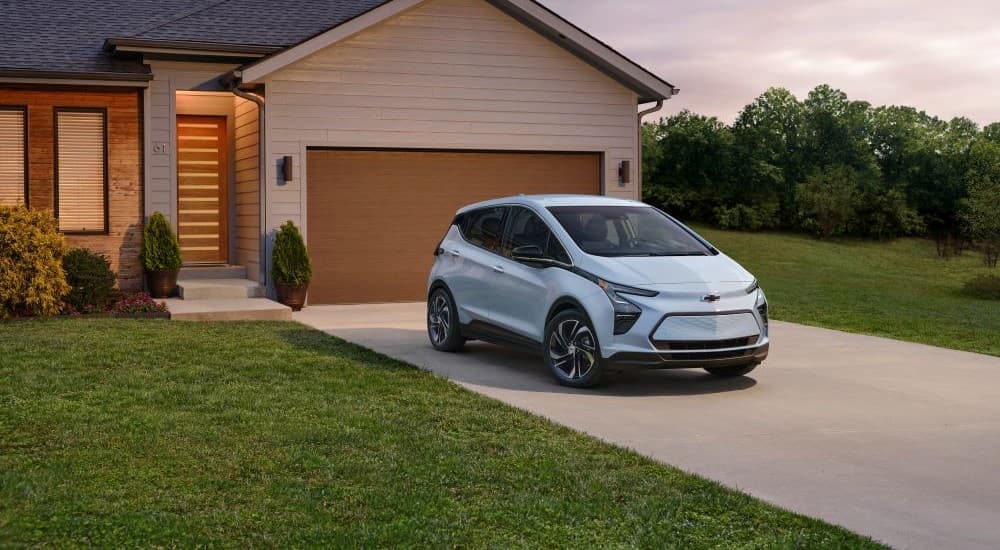 A light blue 2023 Chevy Bolt EV is shown parked on a driveway.