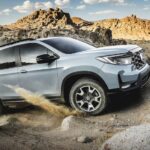 One of many popular Honda SUVs for sale, a light blue 2023 Honda Passport, is shown driving off-road.