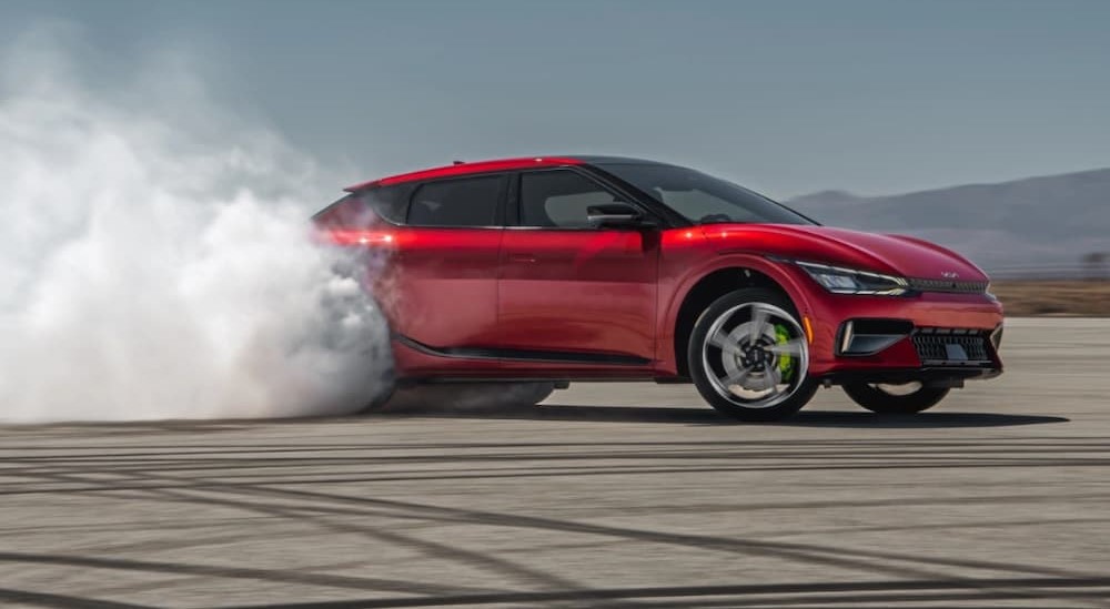 A red 2023 Kia EV6 is shown performing a burnout.