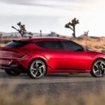 A red 2023 Kia EV6 for sale is shown parked on a highway.