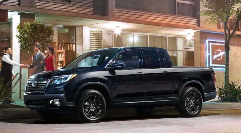 A popular used truck for sale, a black 2020 Honda Ridgeline Black Edition, is shown parked on a city street.