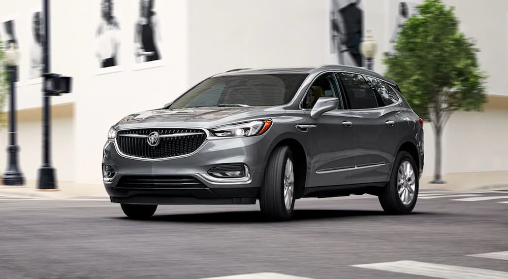 A silver 2021 Buick Enclave is shown driving in a city.