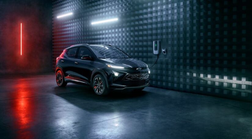 One of the most popular electric cars for sale, a black 2023 Chevy Bolt EUV Redline, is shown driving through a dark tunnel.