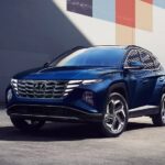 A blue 2023 Hyundai Tucson hybrid for sale is shown parked near a building.