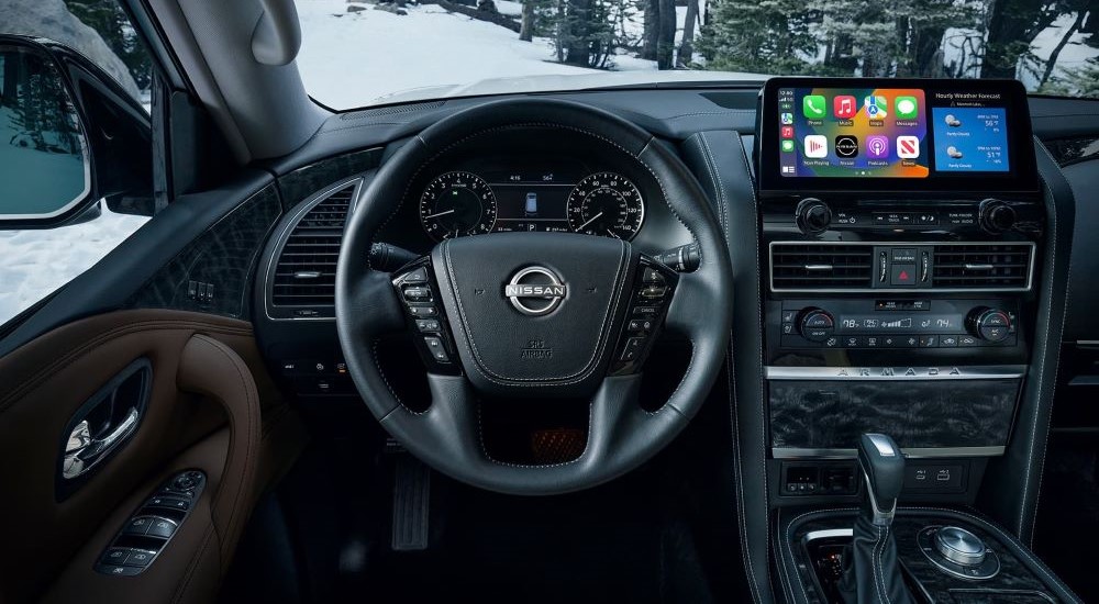 The black interior of a 2023 Nissan Armada is shown, including the wheel and dashboard.