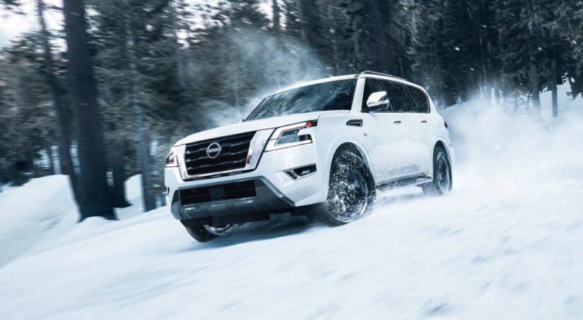 Winner of the 2023 Nissan Armada vs 2023 Chevy Tahoe competition, a white 2023 Nissan Armada, is shown driving through the snow.