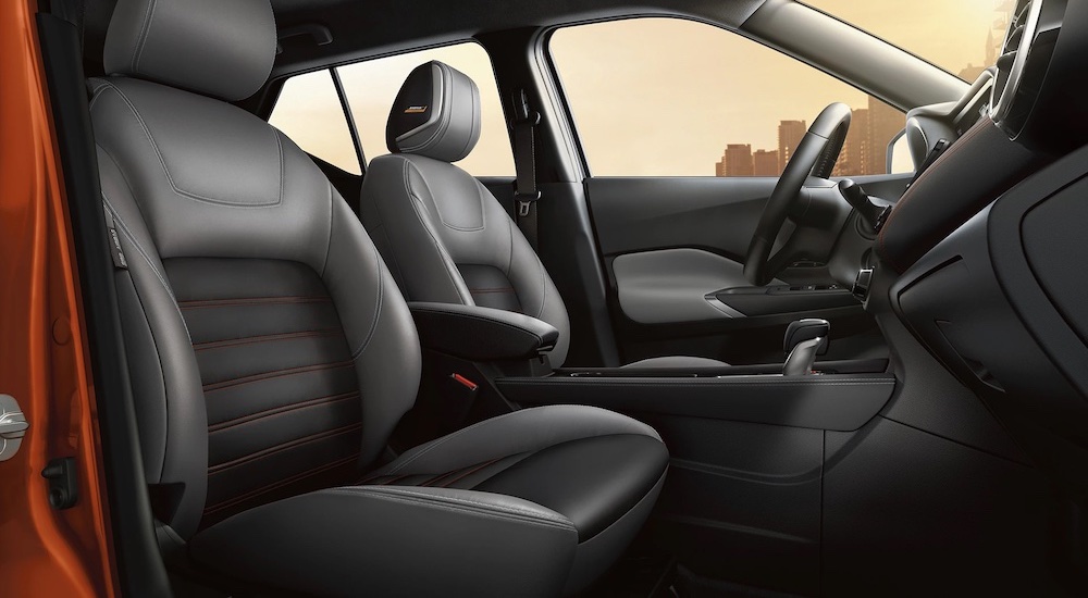 The interior of a 2023 Nissan Kicks SV is shown from the side, including the front seats and wheel.