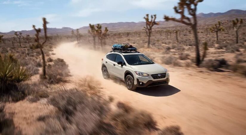 One of the more common used cars for sale, a white 2023 Subaru Crosstrek, is shown driving on a trail.