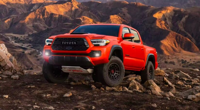An orange 2023 Toyota Tacoma TRD Pro is shown driving off-road after visiting a Toyota dealer to 'rent a Toyota'.