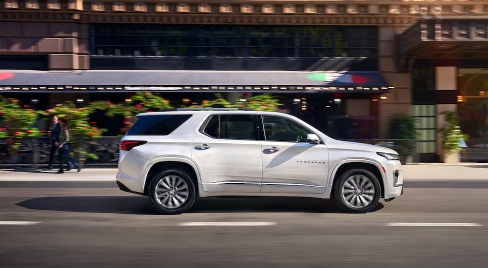 A white 2023 Chevy Traverse is shown driving on a city street.