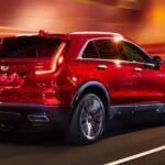 A red 2024 Cadillac XT4 for sale is shown driving on a highway.
