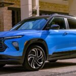 A blue 2024 Chevy Trailblazer RS is shown parked near a Chevy dealer.