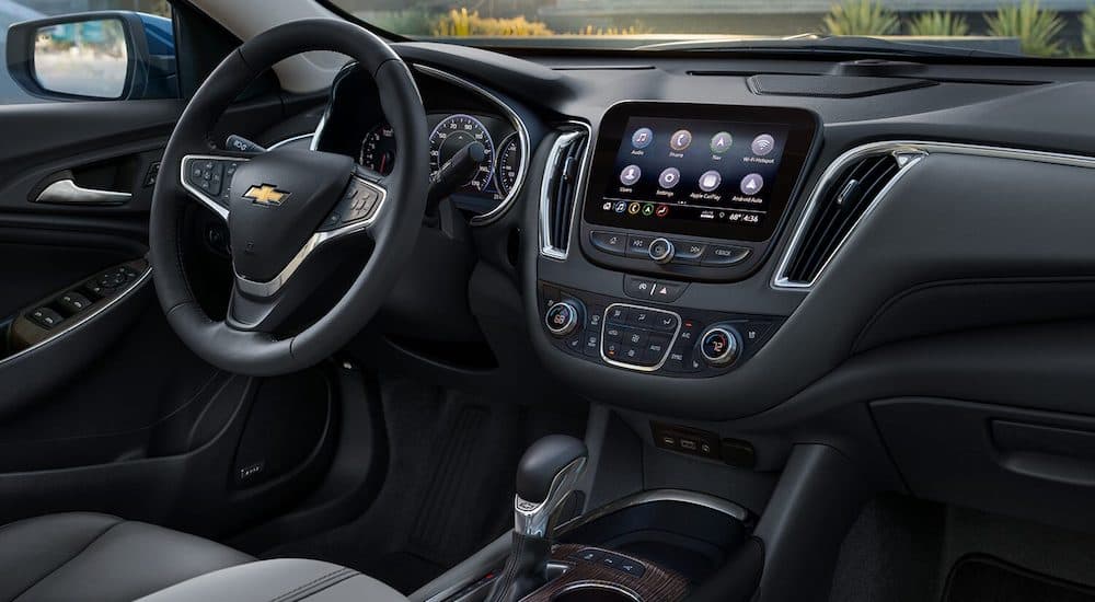 The interior of a 2024 Chevy Malibu is shown, including the dashboard screen and steering wheel.