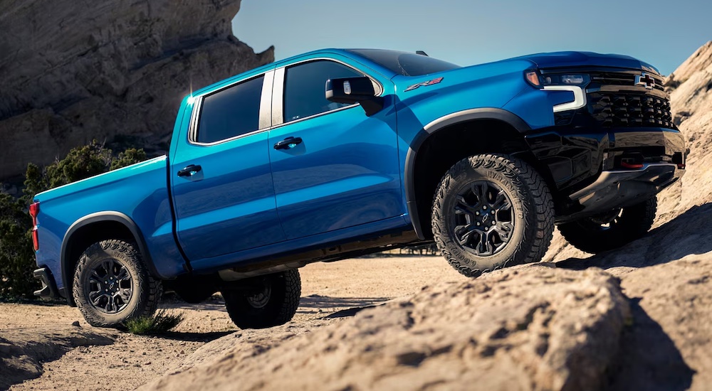 A blue 2024 Chevy Silverado 1500 ZR2 is shown climbing a desert hill.