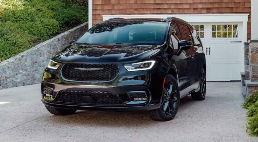 A new Chrysler Pacifica for sale, a black 2024 Chrysler Pacifica, is shown parked in a driveway.