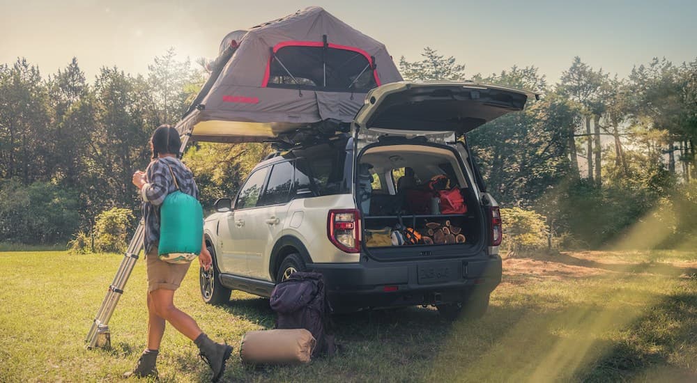 A group of people are shown unloading camping gear from the open hatch of a white 2024 Ford Bronco Sport Badlands.
