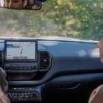 The black interior of the 2024 Ford Bronco Sport Badlands is shown from the back, with two people seen seated in the front seats.
