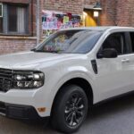 A white 2024 Ford Maverick is shown parked near a live music sign.