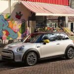 A silver 2024 MINI Cooper SE is shown parked on a city street.