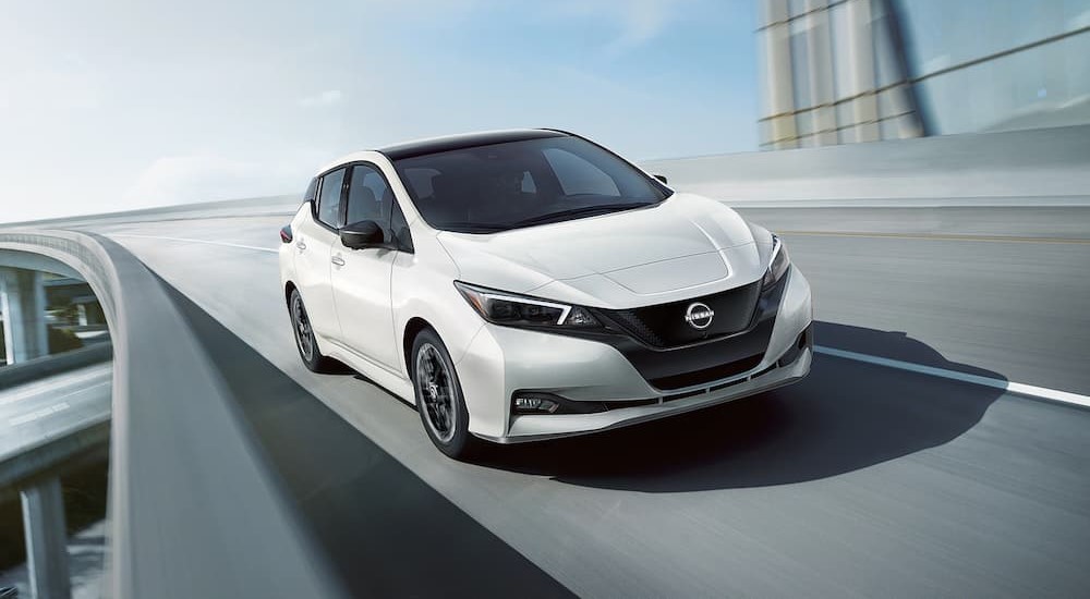 A white 2024 Nissan LEAF SV is shown driving on an overpass.