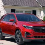 A red 2024 Chevy Equinox Rs is shown parked on a driveway after competing in a 2024 Chevy Equinox vs 2024 Honda CR-V comparison.
