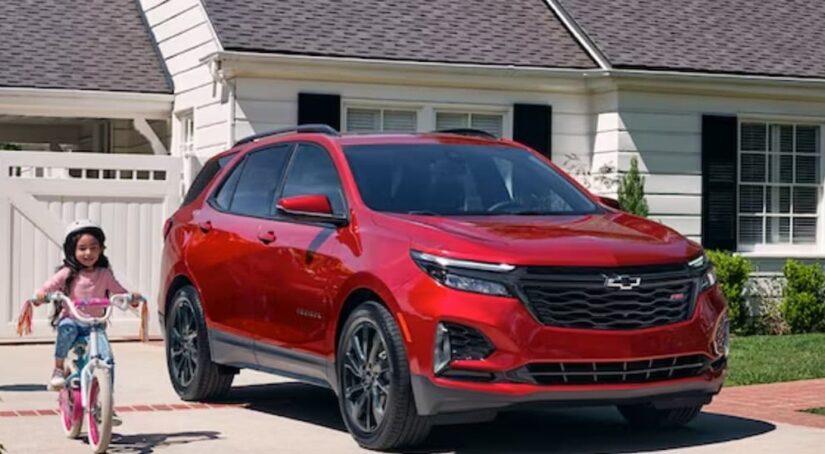 A red 2024 Chevy Equinox Rs is shown parked on a driveway after competing in a 2024 Chevy Equinox vs 2024 Honda CR-V comparison.