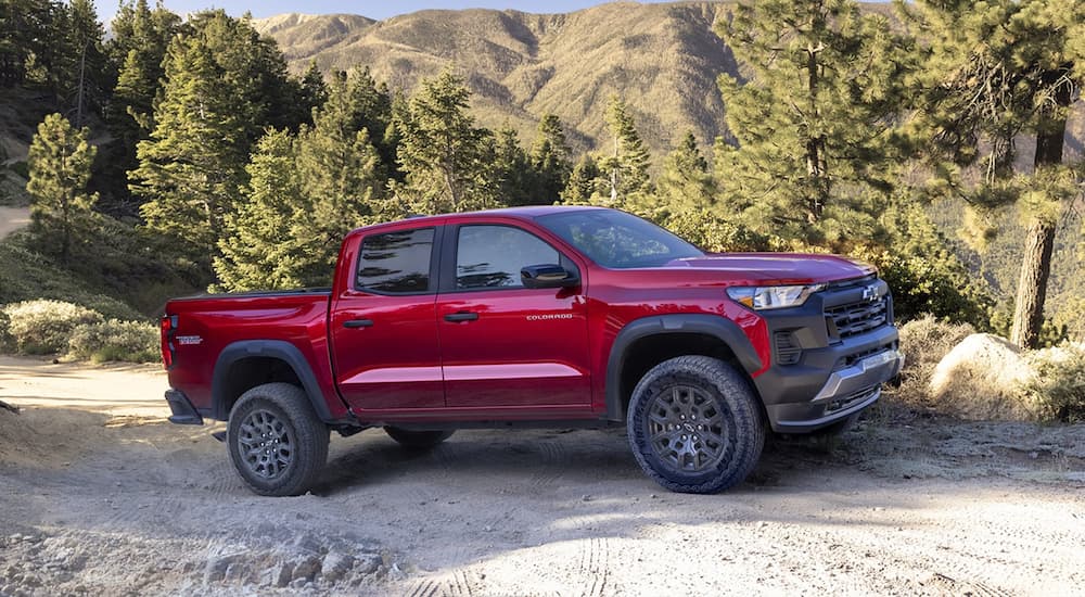 A red 2023 Chevy Colorado ZR2 is shown from the side driving on a dirt road.