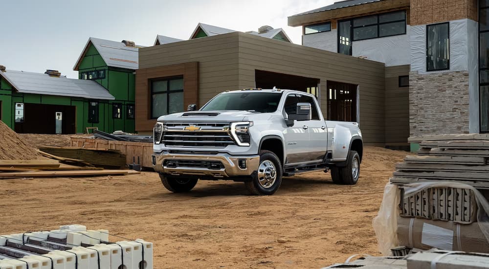 A white 2024 Chevy Silverado 3500HD is shown parked on a home construction site.