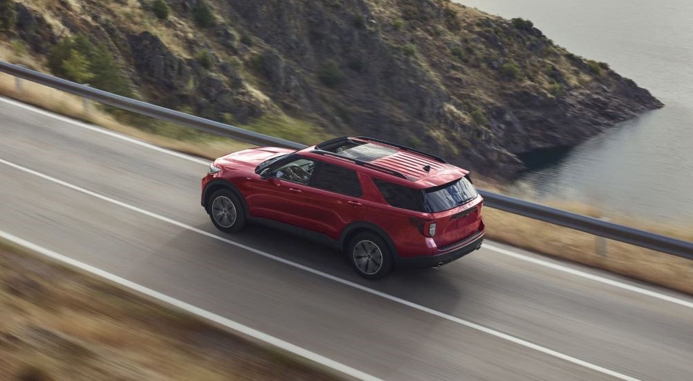 A red 2023 Ford Explorer is shown driving on a coastal road.