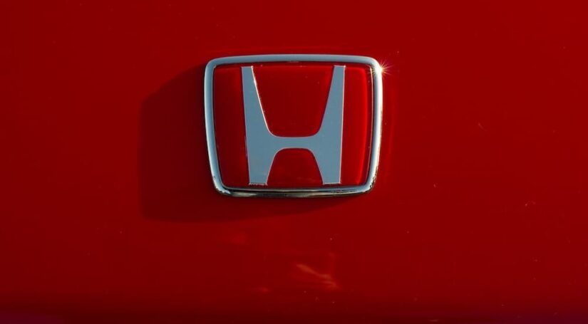 A chrome badge is shown on a red Honda near a used Honda dealer.