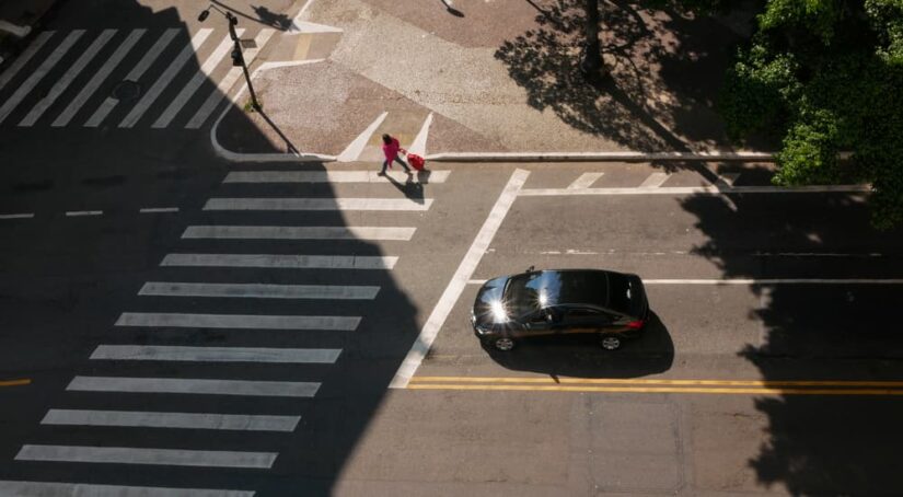 A vehicle is shown stopped at a crosswalk on a city street.