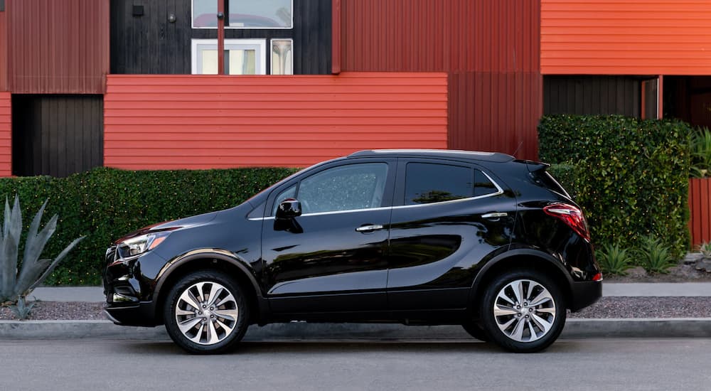 A black 2020 Buick Encore is shown parked near a red house.