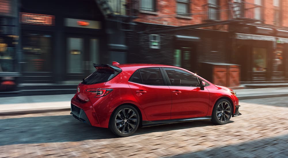 A red 2021 Toyota Corolla Hatchback is shown parked in a city.