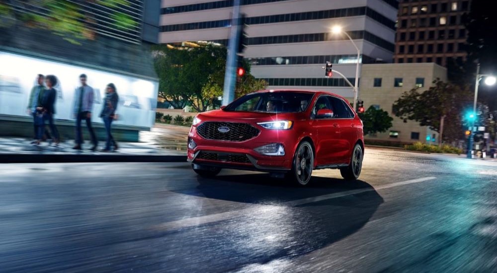 A red 2023 Ford Edge ST is shown driving in a city at night.