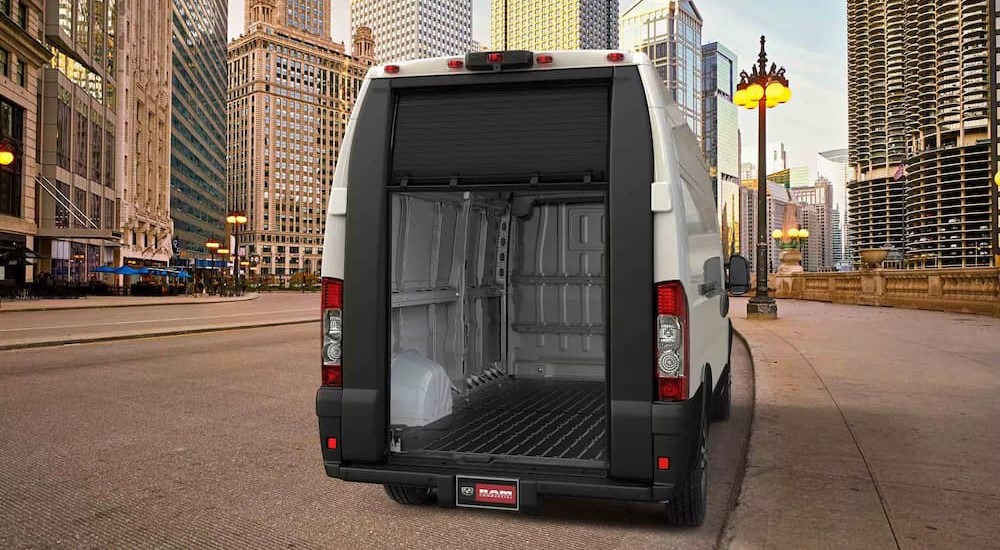 A white 2023 Ram ProMaster is shown parked with its rear door open.
