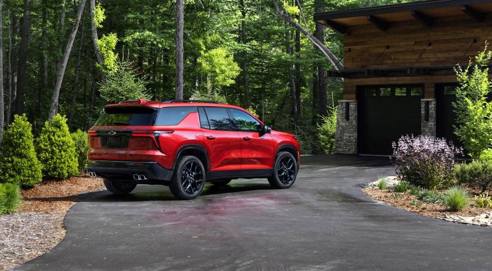 A red 2024 Chevy Traverse RS is shown from the rear on a driveway.