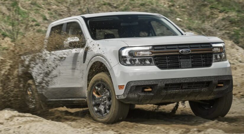 A white 2024 Ford Maverick is shown driving through mud.