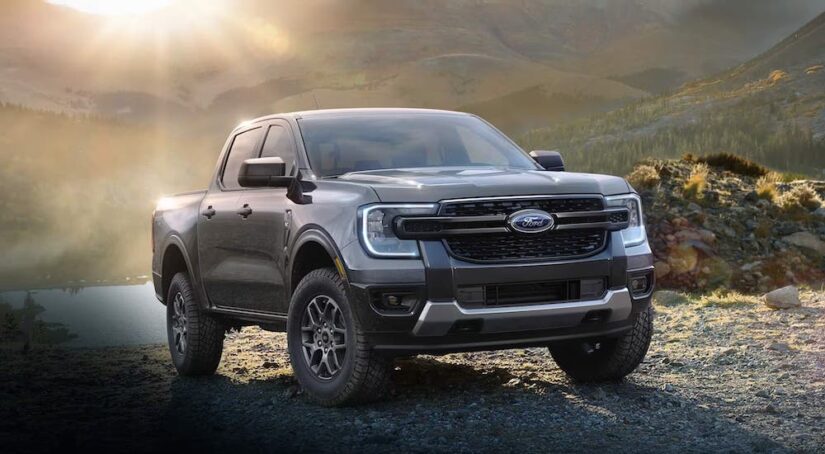 A black 2024 Ford Ranger is shown parked off-road near a lake after visiting a Ford dealership in the city.