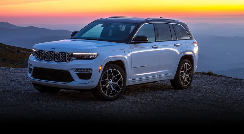 A white 2024 Jeep Grand Cherokee 4xe is shown parked off-road.