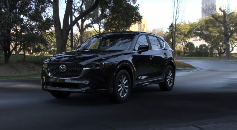 A black 2024 Mazda CX-5 for sale is shown parked on a road,