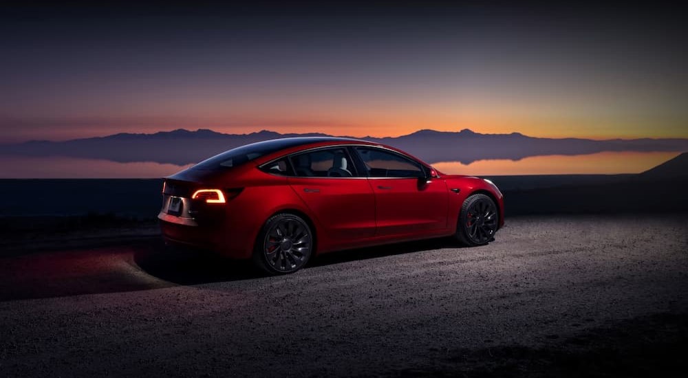 A red 2024 Tesla Model 3 Performance is shown parked at night.