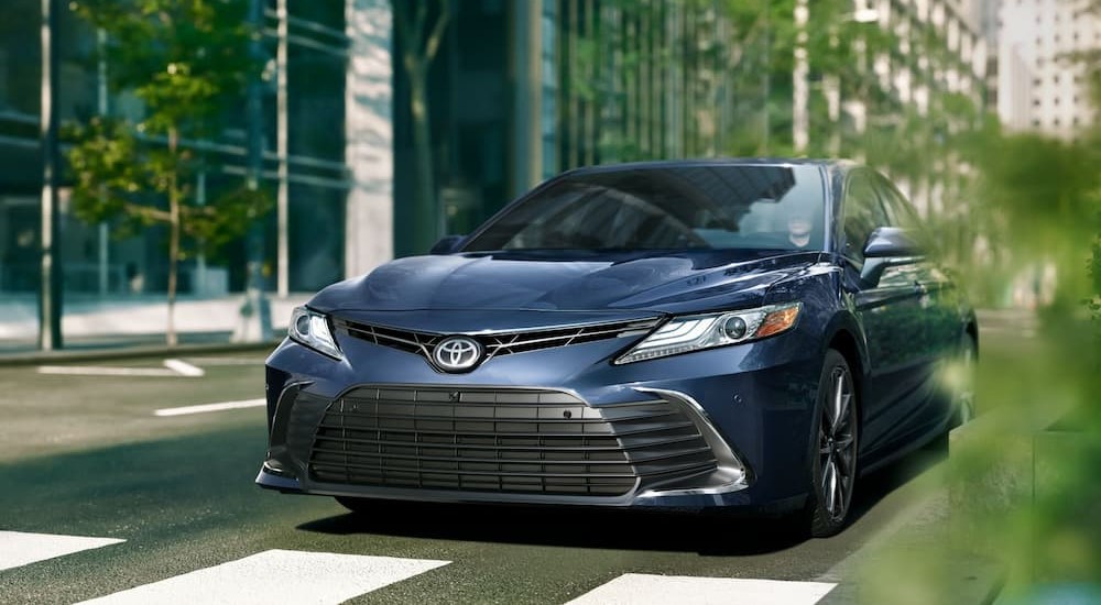 A blue 2024 Toyota Camry XLE is shown driving on a city street.