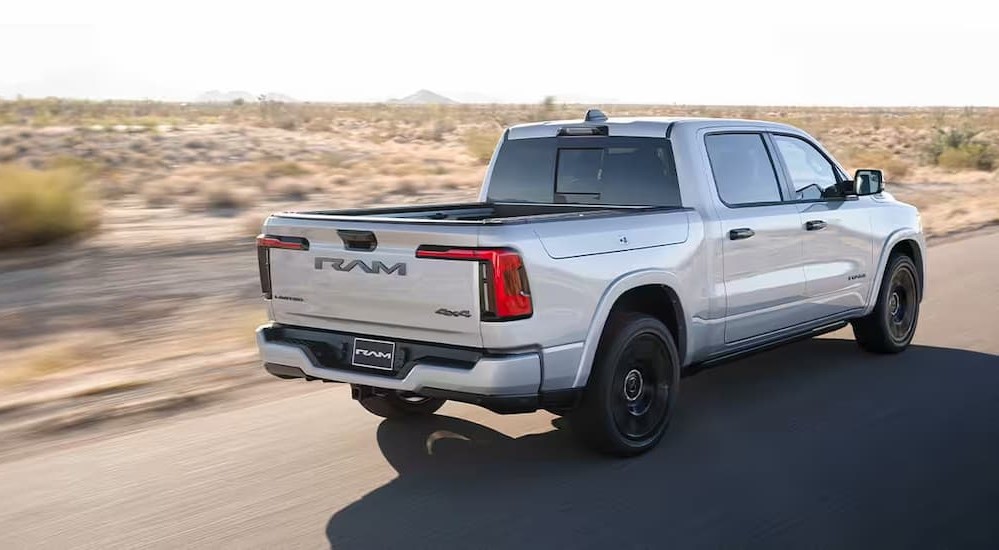 A silver 2025 Ram 1500 Ramcharger is shown driving on a desert road.