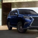 A blue 2023 Lexus GX for sale is shown in front of a modern building.