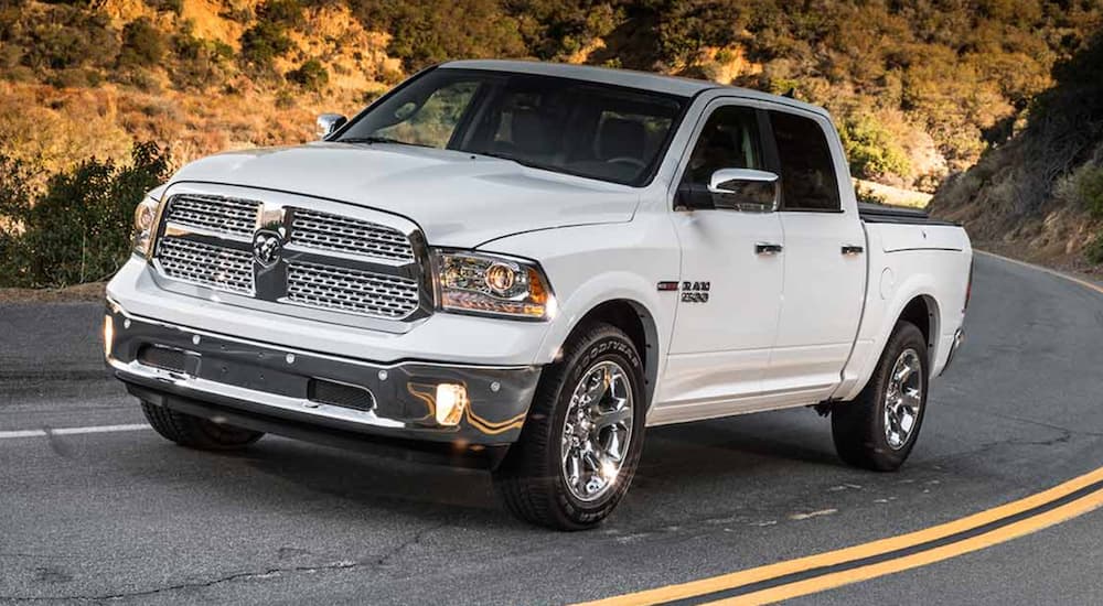 A white 2013 Ram 1500 is shown driving on a highway.