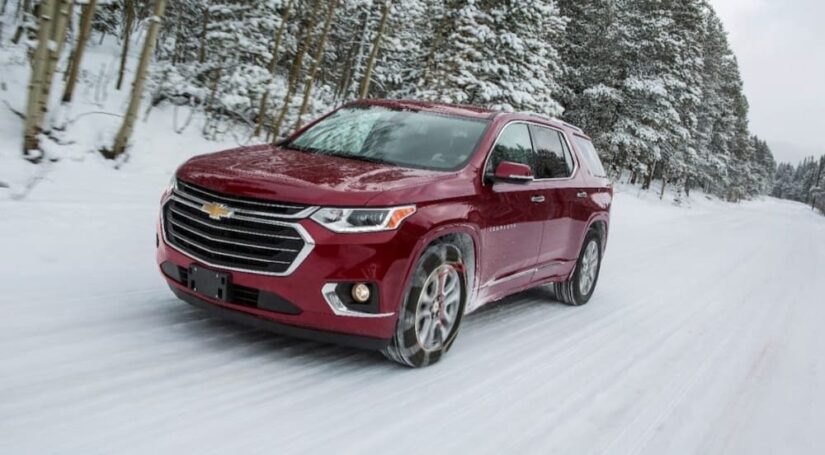 A red 2018 Chevy Traverse is shown driving on a snowy road.