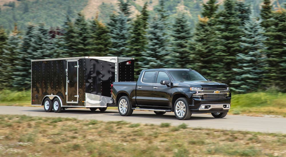 A black 2020 Chevy Silverado 1500 High Country is shown towing a trailer.