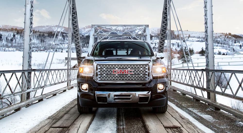 A black 2020 GMC Canyon is shown driving over a snowy bridge.